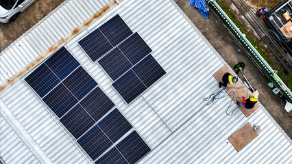 A sustainable energy project featuring solar panels on a roof surrounded by tropical trees,...