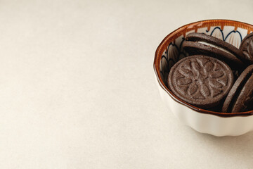 Delicious dark cookies resting in an elegant bowl on a light surface