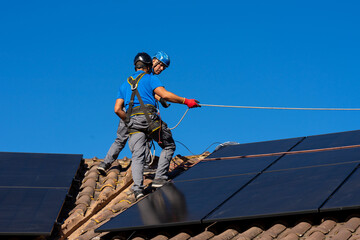 Workers installing solar panels on a roof on a sunny day