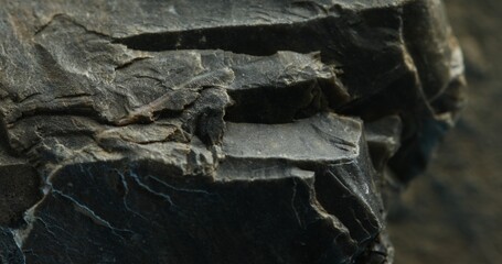 Close-up of cracked dark slate rock with layered texture and rough split