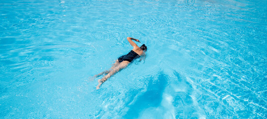 Woman in black swimsuit swimming in the pool.