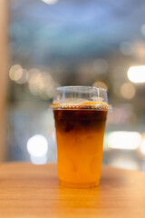 Iced coffee with orange juice sits on a wooden. Dark espresso swirls into the bright citrus juice, creating a layered effect.