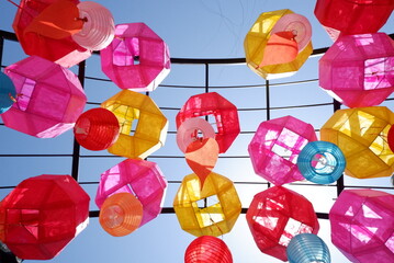 Vibrant multicolored paper lanterns sway gently against a brilliant azure sky