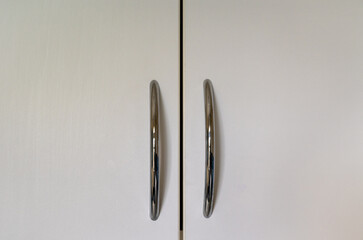 White cupboard doors with silver-colored handles positioned in the center.