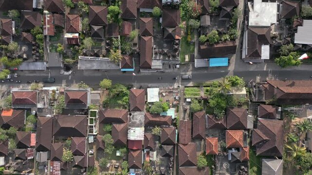 Top-down aerial view of traditional Balinese houses and quiet village road in Ubud, Bali, Indonesia