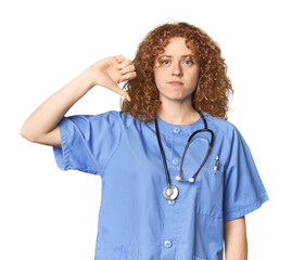 Young Caucasian redhead woman as nurse showing a dislike gesture, thumbs down. Disagreement concept.