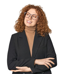 Young Caucasian redhead in business attire smiling confident with crossed arms.