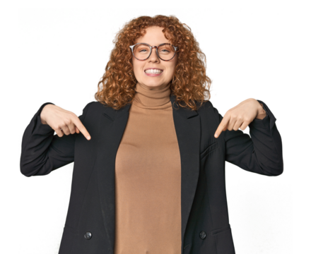 Young Caucasian redhead in business attire points down with fingers, positive feeling.