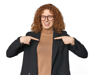 Young Caucasian redhead in business attire surprised pointing with finger, smiling broadly.