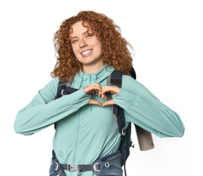 Young Caucasian redhead ready for hiking smiling and showing a heart shape with hands. - Powered by Adobe
