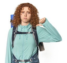 Young Caucasian redhead ready for hiking showing a dislike gesture, thumbs down. Disagreement...