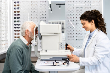 Experienced optometrist checking senior man eyesight focus and diopter using test eyeglasses...