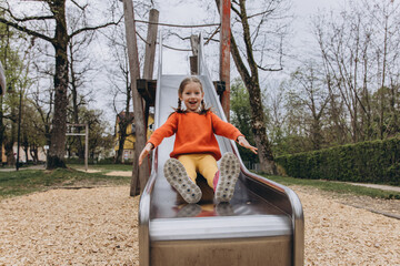 Child sliding down a playground slide with a big smile, enjoying a joyful and carefree moment...