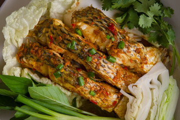  The fish is infused with a flavorful blend of chili and garlic, making it irresistibly appetizing. It's served with a variety of fresh vegetables.