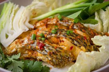  The fish is infused with a flavorful blend of chili and garlic, making it irresistibly appetizing. It's served with a variety of fresh vegetables.