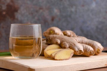 Cup of tea with ginger root on a wooden table, Ginger tea with and honey on a gray background.