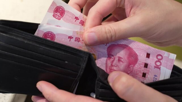 man's finger count Chinese Yuan or RMB in his wallet or purse