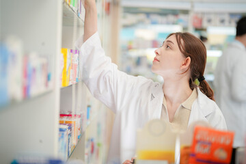 woman pharmacist checks and arranges medicines on pharmacy shelves, emphasizing precision and responsibility in healthcare services. The scene highlights the daily operations in a modern pharmacy.