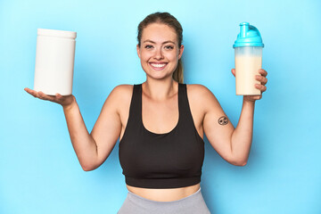 Young blonde sportswoman holding a protein shake in a studio