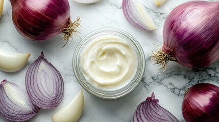 A luxurious skincare composition featuring an elegant jar of onion cream next to sliced red and white onions, set on a marble background.