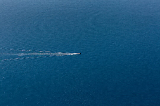 Mer de couleur bleu profond en vue a&eacute;rienne avec un bateau naviguant au centre et &eacute;cume blanche dans son sillage