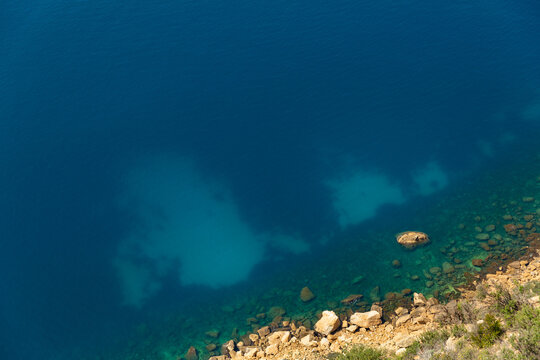 Vue a&eacute;rienne de la mer de couleur bleu et turquoise transparent et un bout de littoral avec des fonds marins, des rochers et de la garrigue de m&eacute;diterran&eacute;e