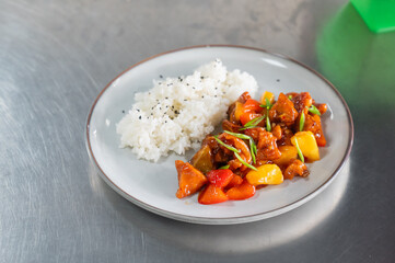Pork in sweet and sour sauce with boiled rice on a plate. 