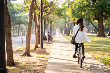 Young Asian woman riding bike in nature public park. Sustainable save energy lifestyle. Commute and...