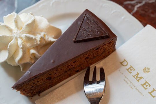 Vienna, Austria - july 3 2024: Slice of Sacher Cake seen from above in a Dish with Whipped Cream Produced by the Historic Viennese confectionery Demel, Austria