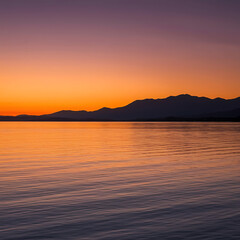 Fototapeta premium Sunset over calm water, mountains in silhouette.