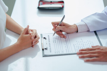 Male doctor or dentist writing report working with tooth x-ray film, model and equipment used in...