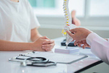 .Asian doctor holding model of bones and spinal cord. Lumbar spine with herniated disc fragment for...