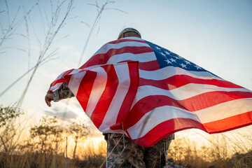 Hand Waving the Flag of the United States of America in memorial day . Us soldier holding American...