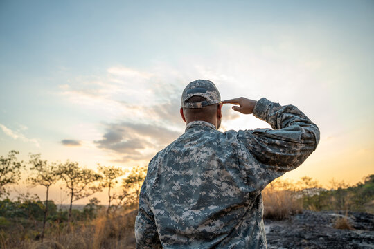 Us Army veteran honors Veterans Day. Man soldier adjusts the US military patch before duty. A US soldier with an American flag patch on his uniform prayers for Memorial Day. Independence Day