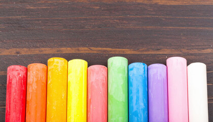 Vibrant Rainbow Colored Chalk in a Row on Dark Wood Background