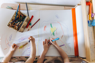 Top View Home: Two little girl drawing with colored pencils, focused and creative, capturing a moment of artistic expression