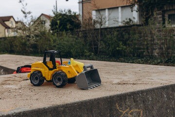 toy yellow bulldozer with sand on children's sandbox, trucks concept, closeup