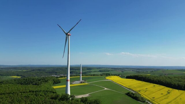 Panoramablick auf eine rotierende Windturbine f&uuml;r Stromerzeugung und einen unvollendeten Turm, Wind Energie und Technologie, Nachhaltige Energie Konzept, 4K, Aerial, Kamerafahrt
