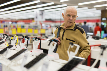 Elderly man examines smart watch in showroom of electronics store