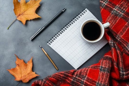 Autumnal workspace coffee notepad pens and plaid blanket