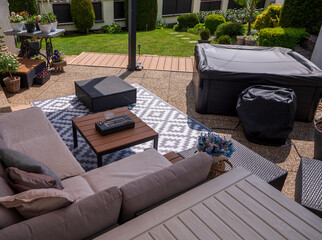 View from patio with outdoor sofa, hot tub, coffee tables, and decorative rug on stone tiles,...