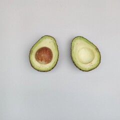 Halved Fresh Avocados Showcasing the Pit and Creamy Inner Fruit on White