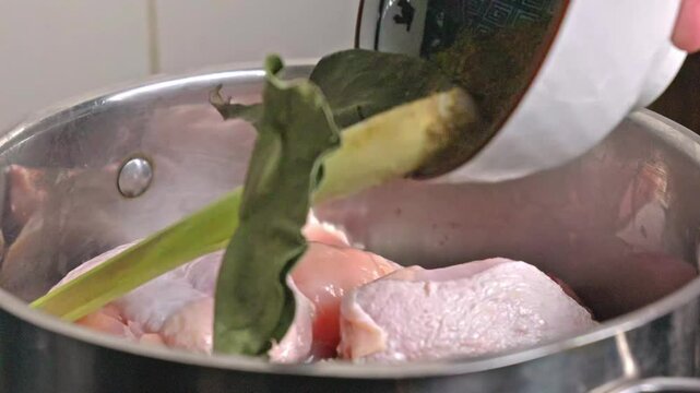 dry seasoning being added to raw chicken before it's cooked in a pot, handheld, slow motion