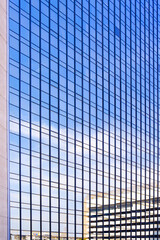 Skyscraper with light reflection of blue sky on glass building wall surface, Modern architecture geometric pattern vertical background in minimal design