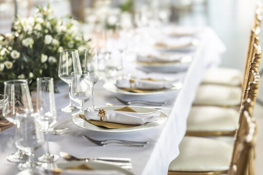 A wedding table covered with a white tablecloth, decorated with flowers, candles, glasses and cutlery