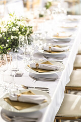 A wedding table covered with a white tablecloth, decorated with flowers, candles, glasses and cutlery