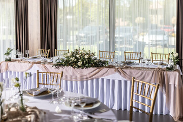 A wedding table covered with a white tablecloth, decorated with flowers, candles, glasses and cutlery
