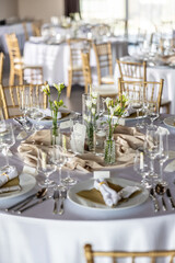A wedding table covered with a white tablecloth, decorated with flowers, candles, glasses and cutlery