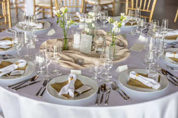 A wedding table covered with a white tablecloth, decorated with flowers, candles, glasses and cutlery