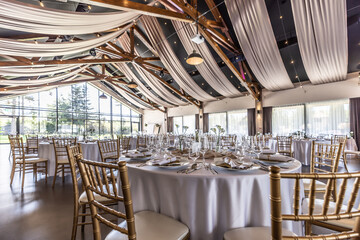 Wedding setting and decorated tables in a beautiful modern interior of a performance hall with a modern light ceiling of wooden construction